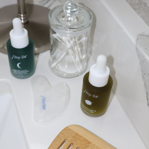 Two skincare bottles with droppers on a bathroom counter.