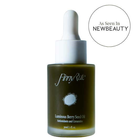 A bottle of Luminous Berry Seed Oil with a dropper cap, branded by Jiny Rue, positioned against a white background with a text overlay stating 'As Seen In NEWBEAUTY'.